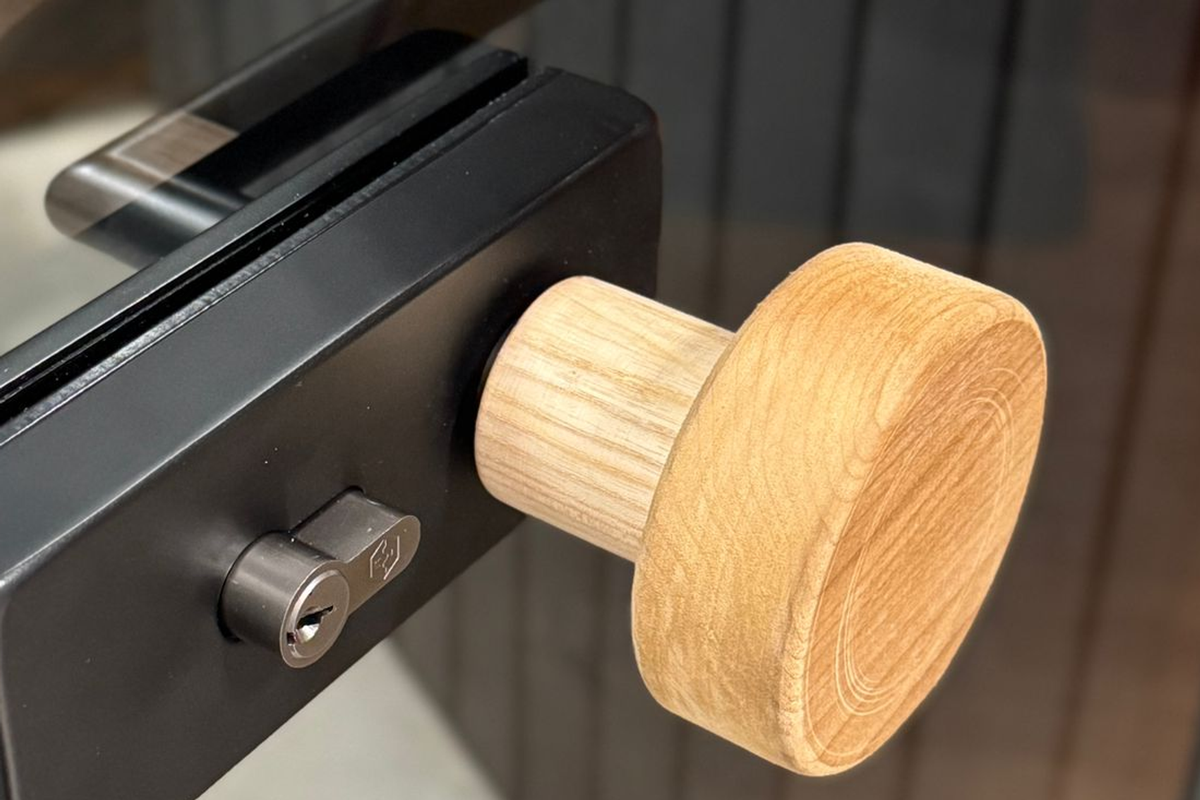 Photographed glass-door hardware and timber grip shown only as a physical operability interface.