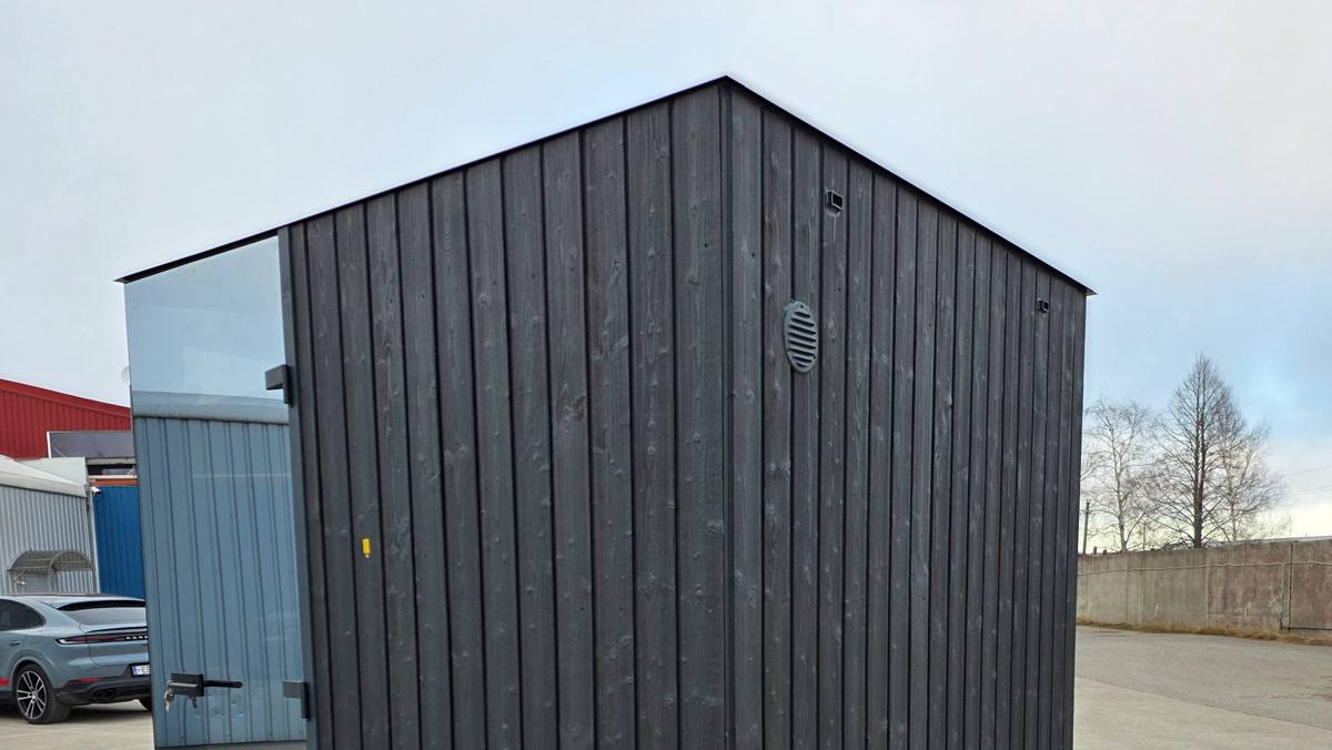 Dark timber side cladding, a door edge and an exterior vent on a cube sauna.